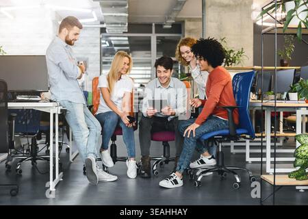 Team Members Collaborate in Modern Office While Reviewing Project on Tablet at Midday Stock Photo