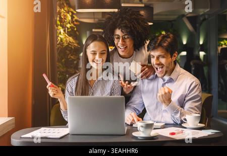 Successful business team looking at laptop happily Stock Photo