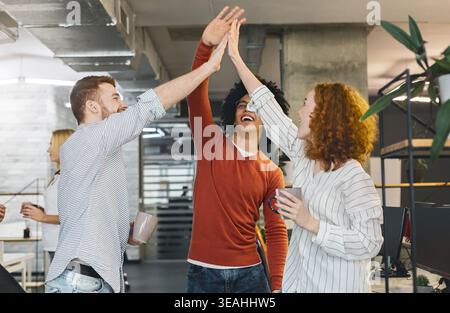 Happy coworkers having fun, giving high five during coffee break Stock Photo