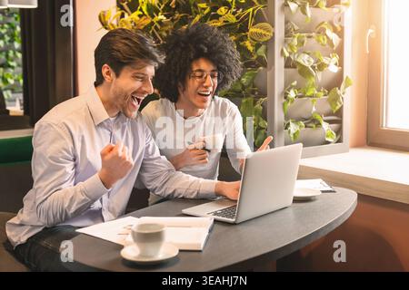 Happy millennial men looking at laptop enjoying great news Stock Photo