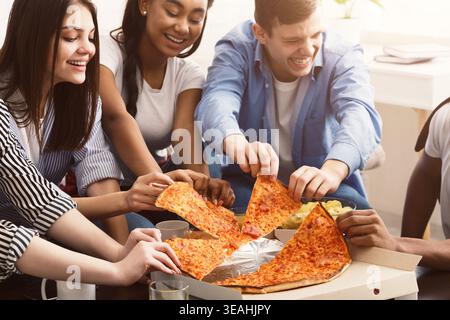 Friends taking slices of hot pizza from cardboard box Stock Photo