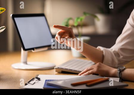 Businesswoman's hands with tablet computer using virtual screen in office at night, closeup. Customer experience concept Stock Photo