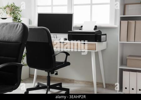 Modern workplace with computer and printer near window in office Stock Photo