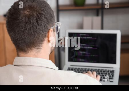Portrait of male programmer working with laptop in office, back view Stock Photo
