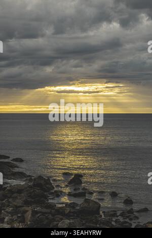 A breathtaking blazing golden sunset with the sun's brilliant reflection shimmering across the calm Lofoten sea in August Stock Photo