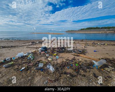 Balikpapan, Indonesia - April 14, 2026.  A wide shot of a sandy coastline littered with plastic bottles, cups, and various debris. Stock Photo