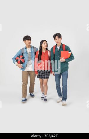 Three students from different cultural backgrounds walk together on a campus. Stock Photo
