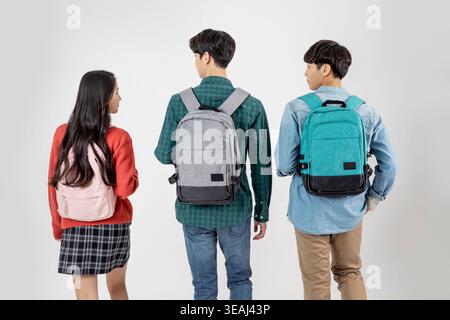 A group of diverse high school students stand together, looking at a teacher or peer, in a modern classroom setting. Stock Photo