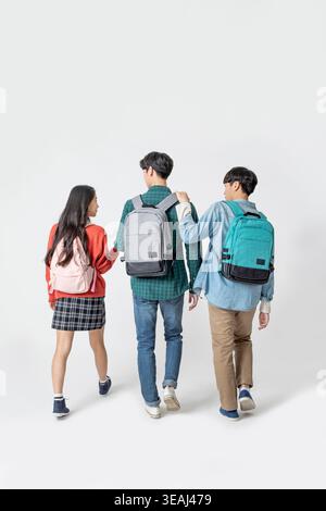Three students walking together, each with a backpack, against a white background. Stock Photo