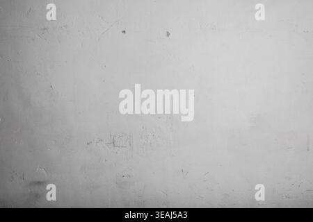 A worn, white concrete wall with small cracks and scratches is exposed to the light. Stock Photo