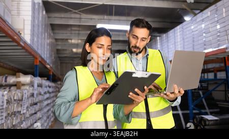 Two warehouse workers using laptop working together in storage aisle Stock Photo