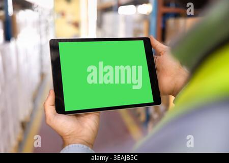 Male worker using digital tablet with green screen in warehouse Stock Photo