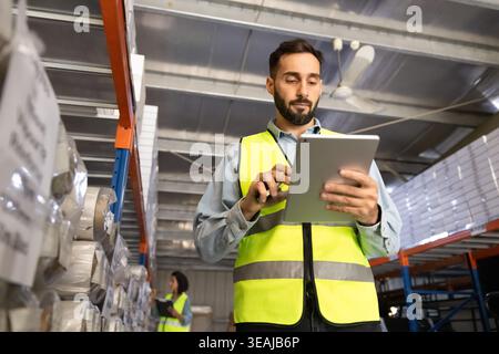 Hispanic male worker using digital tablet in warehouse Stock Photo