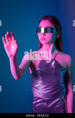 A woman wearing a futuristic VR headset, reaching out to interact with a virtual environment. Stock Photo