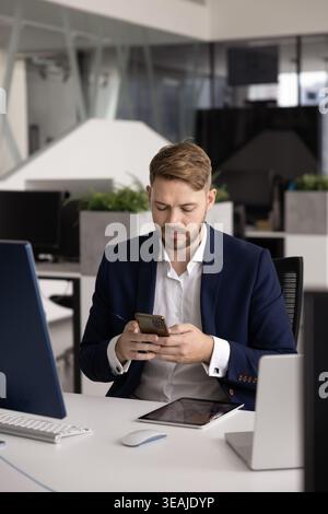 Businessman in suit using smartphone sit at desk in office Stock Photo
