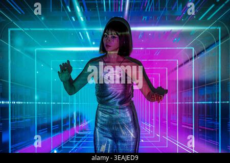 A woman in a futuristic virtual reality environment, interacting with a virtual interface with her hands. Stock Photo