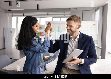 Young multiethnic colleagues celebrating joint success with high five gesture Stock Photo
