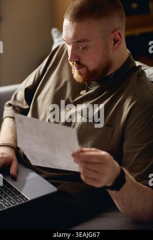 Adult Man Reading Court Document during House Arrest at Home Stock Photo