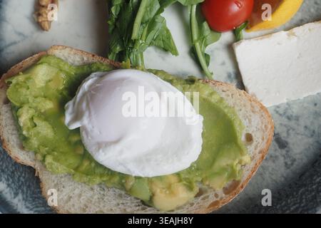 Fresh avocado toast with poached egg and salad on plate Stock Photo
