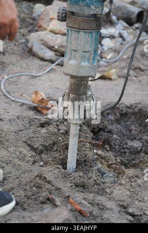 Worker uses tool to dig in ground for construction task Stock Photo
