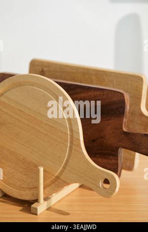 A selection of cutting boards of various sizes and shapes are arranged on a wooden table. Stock Photo