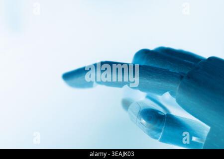 Side view close-up of a neon blue robotic hand pointing with the index finger, isolated on a clean white background with copy space. Futuristic concep Stock Photo