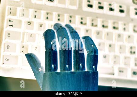 Close-up side view of a neon blue robotic hand interacting with a computer keyboard in a futuristic setting. The image represents artificial intellige Stock Photo