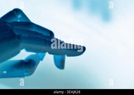 Close-up of a neon blue robotic index finger pointing, isolated on a clean white background with ample copy space. Designed as a futuristic concept id Stock Photo