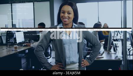 Standing woman in blazer skirt posing hands on hips in open office, code overlay Stock Photo