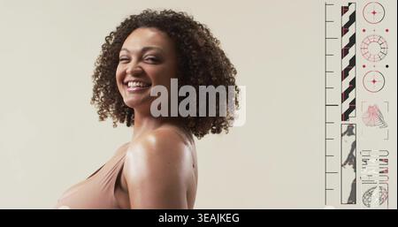 Smiling woman posing three-quarter on beige backdrop, in beige sleeveless top, showing right panel Stock Photo