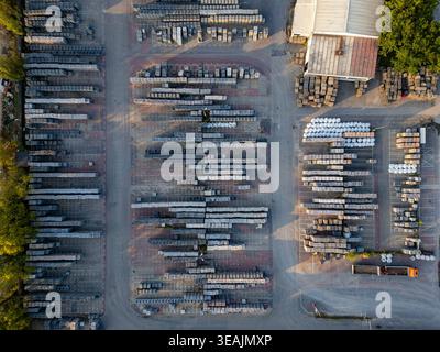 Aerial view of neatly organized rows of construction materials and stone pallets in an industrial storage yard with a truck and surrounding trees Wars Stock Photo