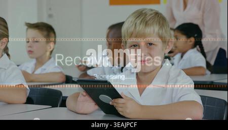 Using tablet front boy doing digital task in class in white collared shirt receiving files overlay Stock Photo