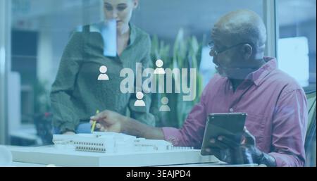Pointing man in pink shirt and woman in green blouse reviewing model in studio with tablet Stock Photo