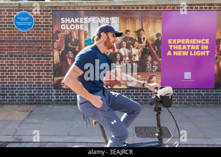 England, London, Southwark, Man on Bicycle Passing by Shakespeare's Globe Theatre Stock Photo