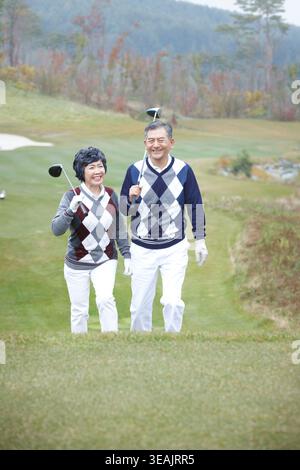middle aged couple walking on golf field Stock Photo