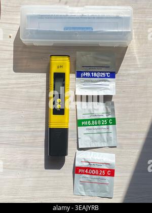 Digital PH Meter With Test Strips, Yellow Handheld Pen Beside Clear Plastic Storage Case And Three Calibration Stock Photo