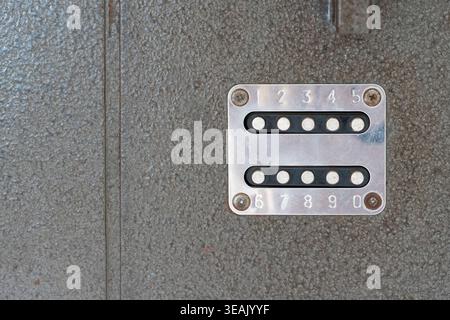 Close-up of a numbered door code lock metal plate with two rows of circular holes and engraved digits, mounted on a textured surface, industrial acces Stock Photo