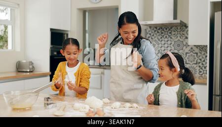 Dance, baking and mom with kids in kitchen for bonding with pastry, dough and prepare dessert. Family, happy and mother with girls excited for helping Stock Photo