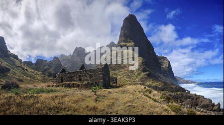 Stone ruins of old houses made of volcanic stone against a spectacular mountain backdrop with thick clouds and blue sky, hiking, lost place, abandoned Stock Photo