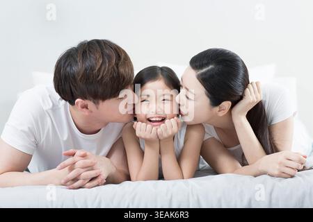 Portrait of loving parents kissing to their daughter Stock Photo