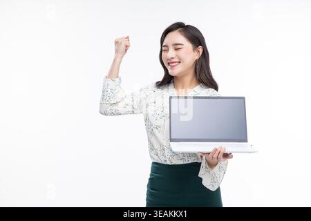 A young woman is holding a laptop and smiling, isolated on a white background. Stock Photo