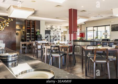 Spacious and stylish restaurant interior with neatly arranged wooden tables and chairs, buffet counter, and wine display at Agua Hotels Riverside in L Stock Photo