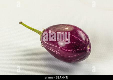 Fresh, raw striped eggplants on a rustic background. This still life highlights the vibrant purple white colors of the vegetables. Ideal for healthy e Stock Photo