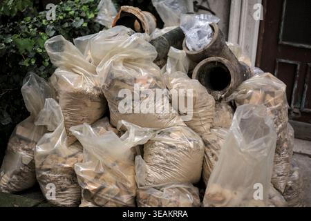 A pile of construction debris and rubble packed in plastic bags, with old pipes on top, ready for removal. Stock Photo