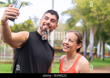 Fit trainer taking selfie with mature woman client in outdoor park after workout Stock Photo