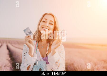Woman instant photos lavender happy young woman holds polaroid pictures in a blooming field at sunset with copy space Stock Photo