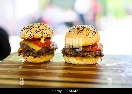 Close-up of a freshly prepared smash cheeseburger with double beef patties, melted cheese and sesame bun placed on a wooden surface, showcasing juicy Stock Photo