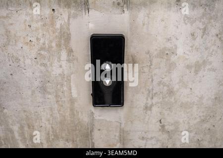 Elevator control panel with up and down buttons on concrete wall, minimal industrial interior detail Stock Photo