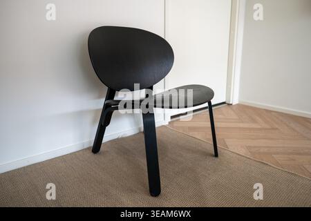 Modern black wooden chair in minimalist interior on carpet near white wall Stock Photo