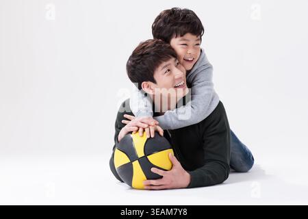 a father and a son lying on the ground with a basketball Stock Photo